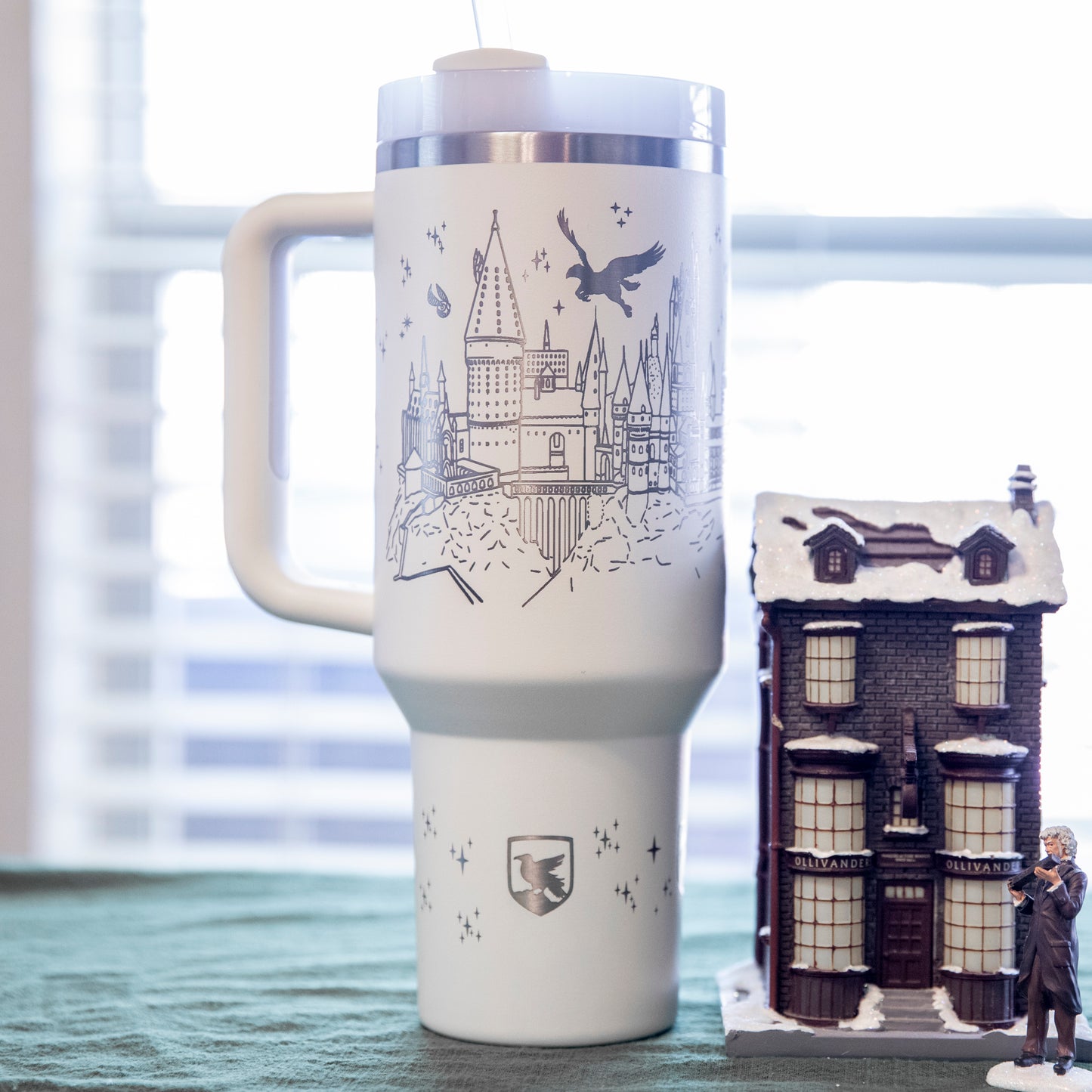 a travel mug sitting next to a toy house