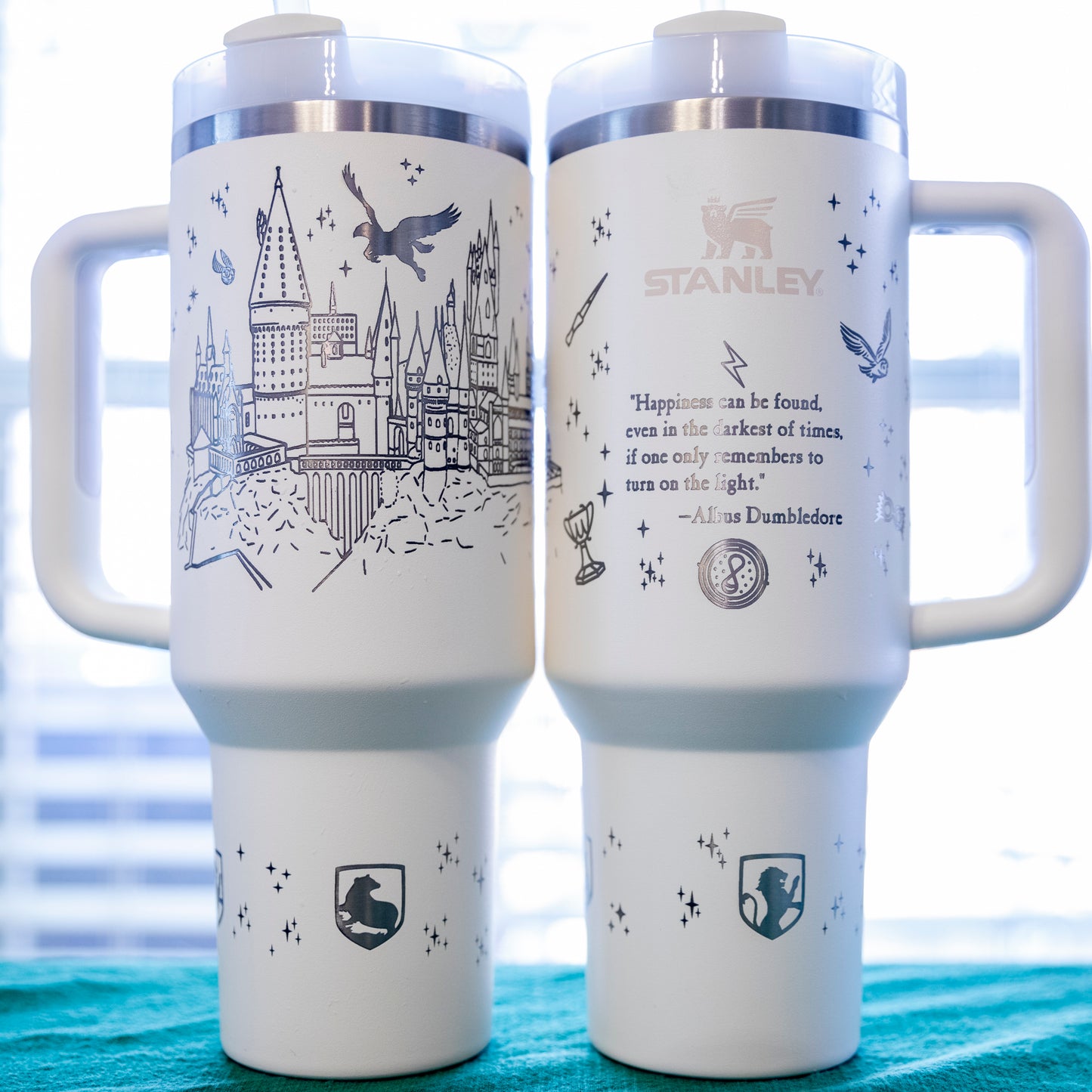 two travel mugs sitting on top of a bed