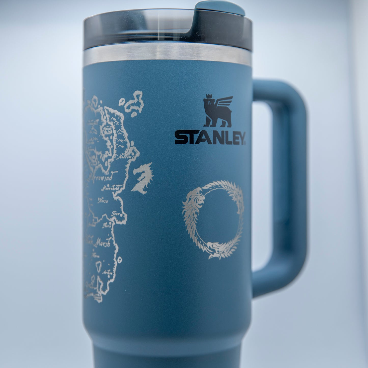 a stainless steel travel mug with a blue handle