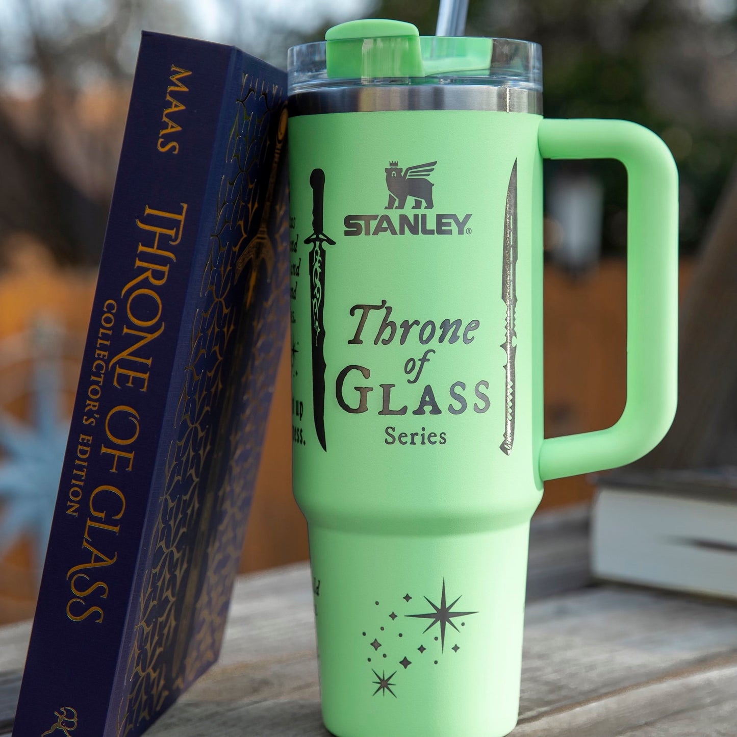 a green travel mug sitting next to a book