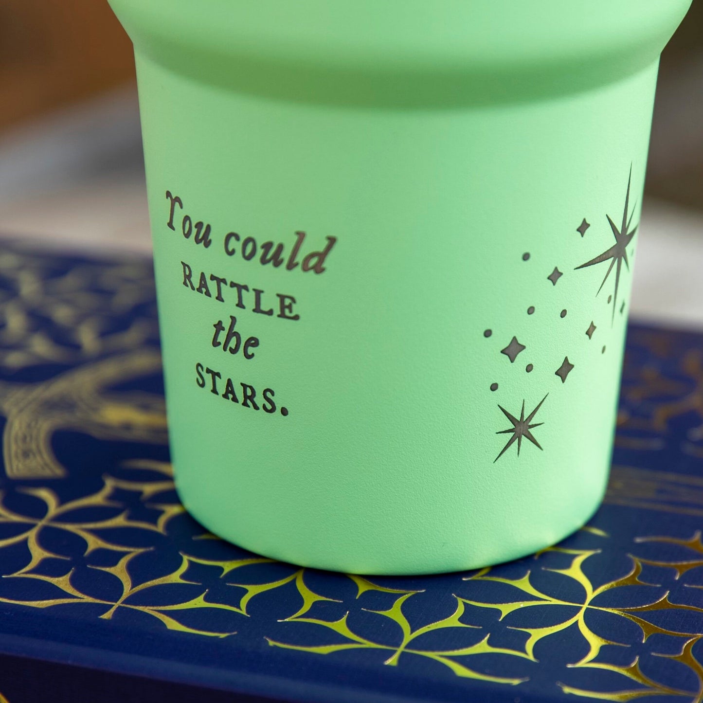 a green cup with writing on it sitting on a table