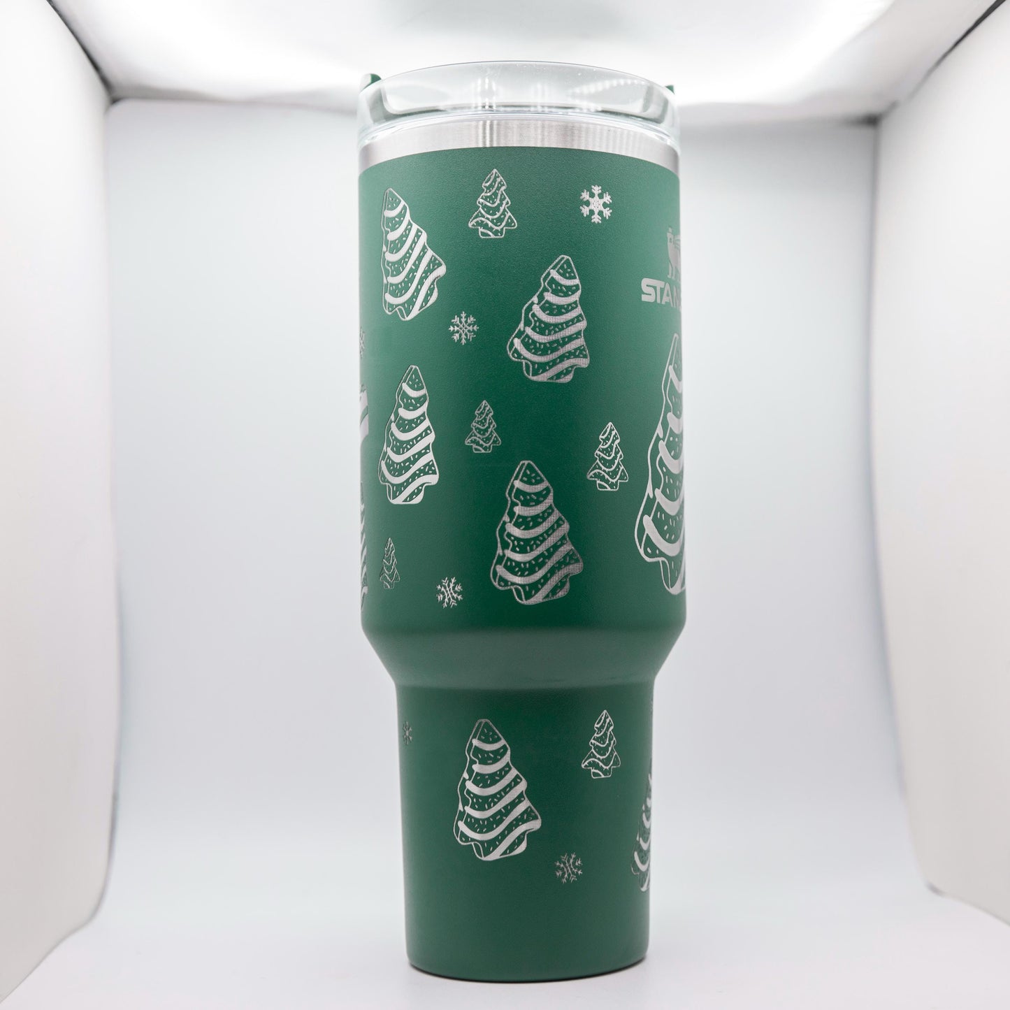 a green cup with white christmas trees on it