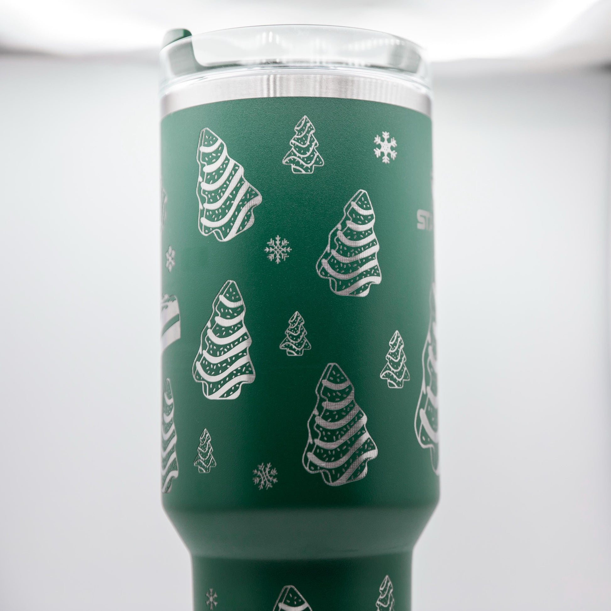 a green cup with white christmas trees on it